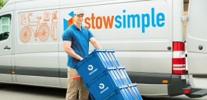 Young Delivery Man Holding Trolley With Stow Simple Boxes